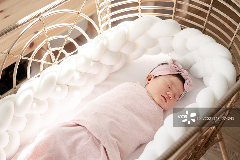 藤摇篮粉色睡袋中的新生女婴图片素材