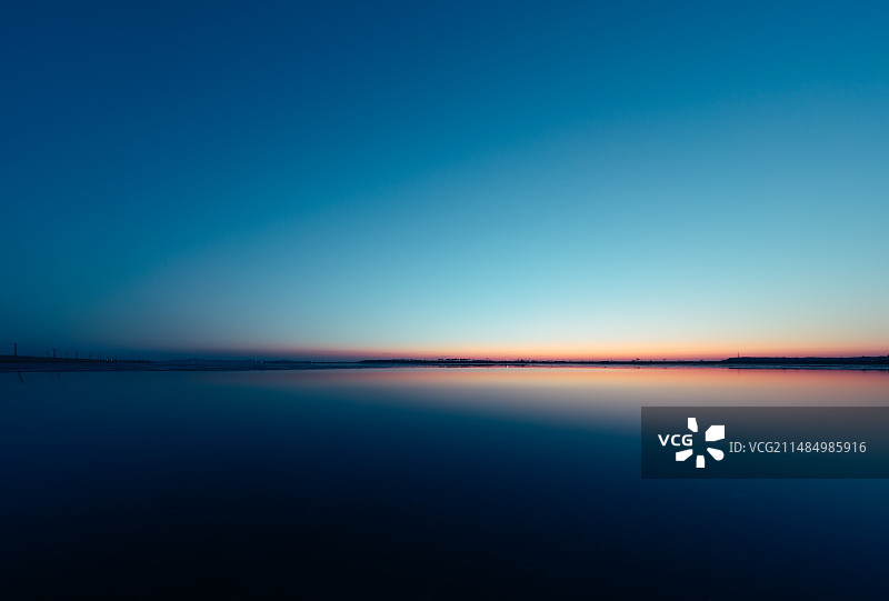 日落时天空倒映在平静的海面上图片素材