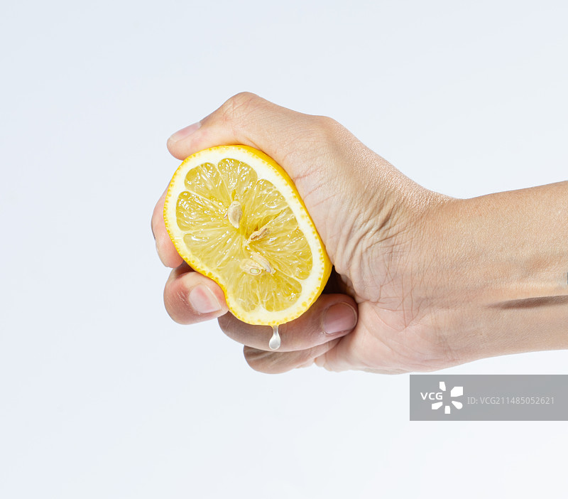 白色背景下手持柠檬的特写镜头图片素材