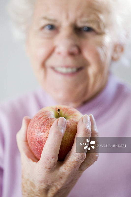 手持苹果的老年妇女图片素材