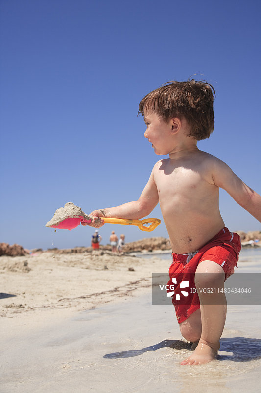 男孩在沙滩玩铲子图片素材