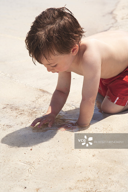 男孩在海滩上探索沙滩和海洋图片素材