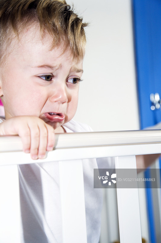 在婴儿床里不开心的幼儿图片素材
