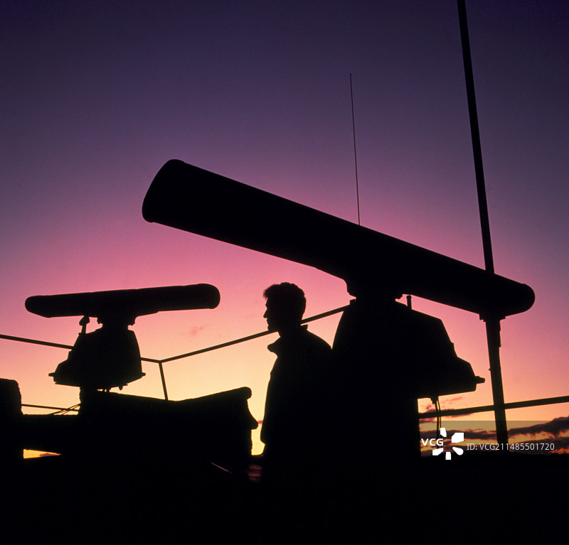 在船的雷达桅杆旁的男人的剪影图片素材