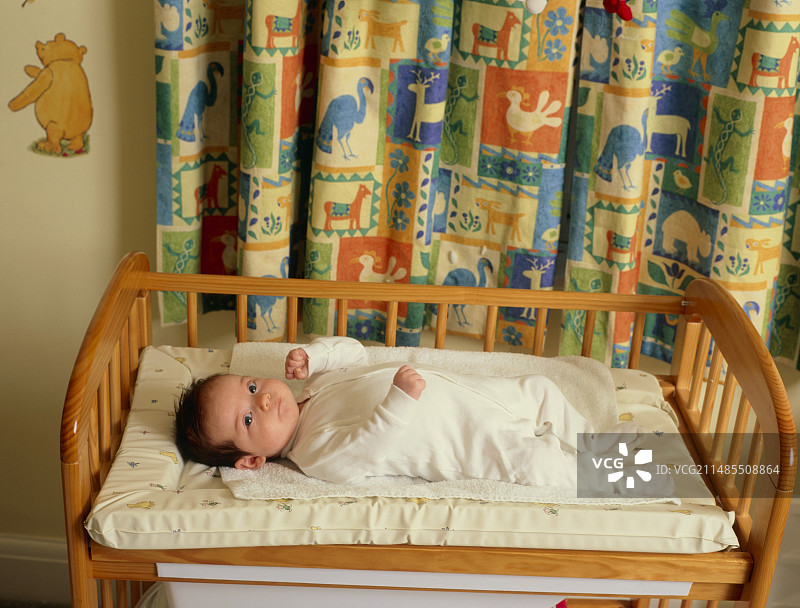 宝宝醒着仰卧在婴儿床里图片素材