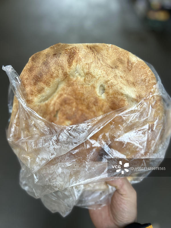 不规则的手拿着塑料袋里的大饼图片素材
