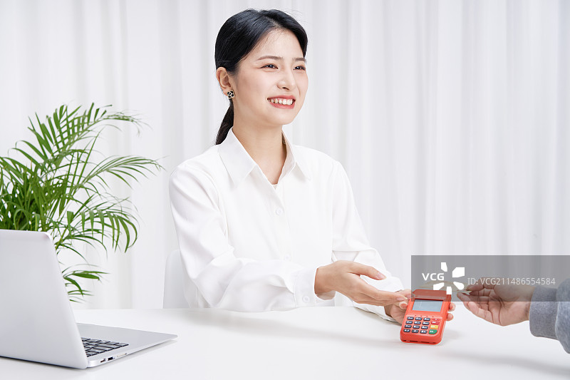 为客户进行刷卡服务的年轻女性图片素材