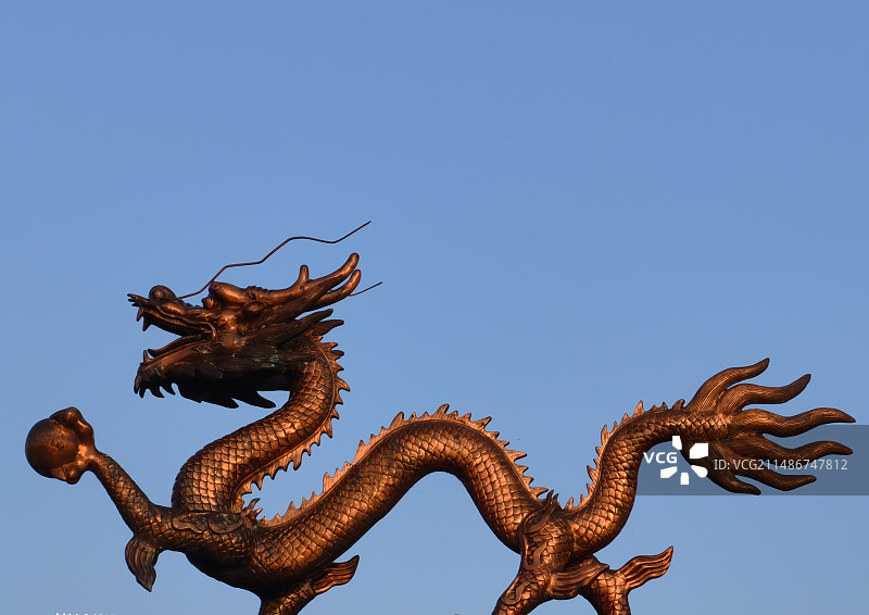 蓝天背景下的金属中国龙雕塑图片素材