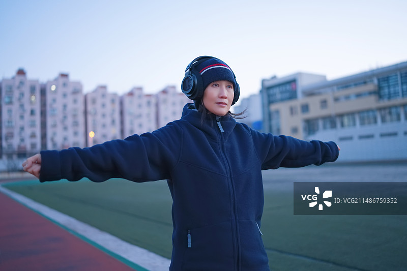 女人在黄昏时分在赛道上伸展手臂图片素材
