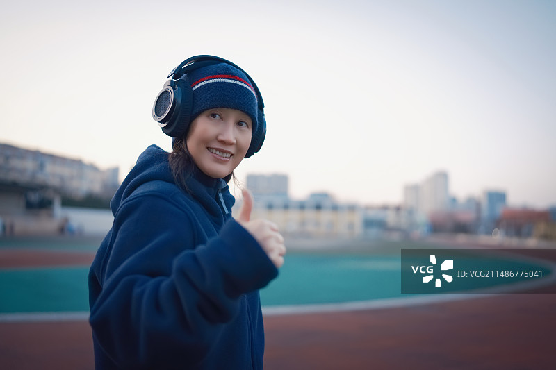 戴着耳机的年轻女子竖起大拇指图片素材