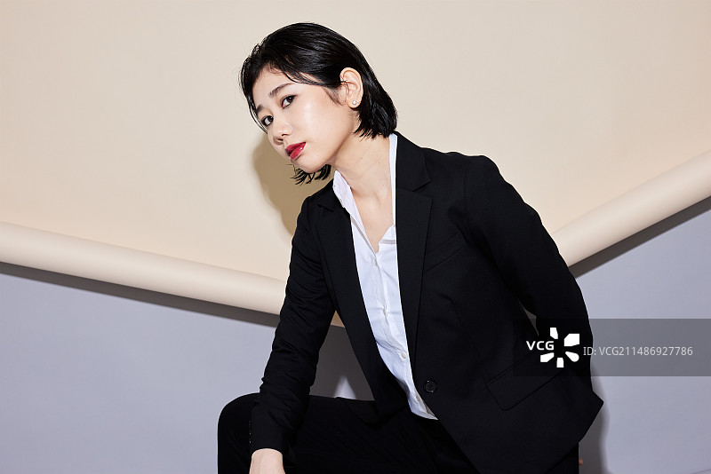 一位身穿商务套装的女子靠墙站立图片素材