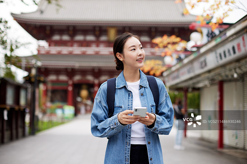 身穿牛仔夹克的女人站在宝塔前图片素材