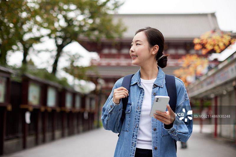 走在街上拿着手机的亚洲女人图片素材
