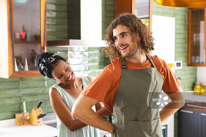多元化夫妇在厨房系上围裙一起做饭图片素材