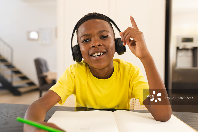 年轻的非裔美国男孩戴着耳机在网上学习图片素材