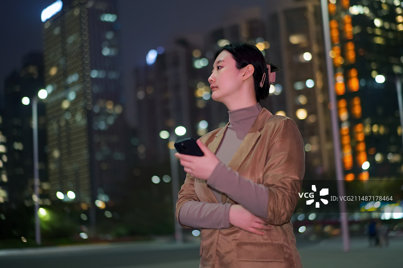 职业女性拿着智能手机行走在城市金融区街道上图片素材