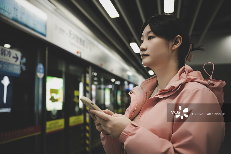年轻女子在地铁站检查电话图片素材