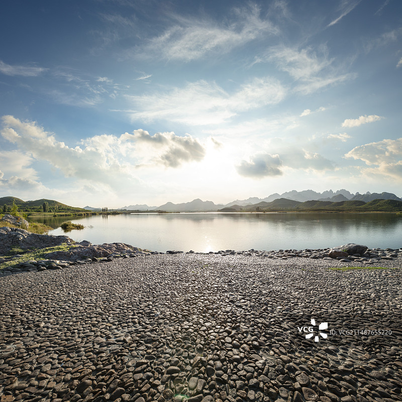 鹅卵石地面平台与日落时的山川湖水，汽车广告背景图图片素材