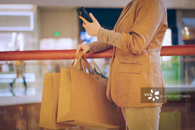 使用智能手机的消费者带着购物袋图片素材