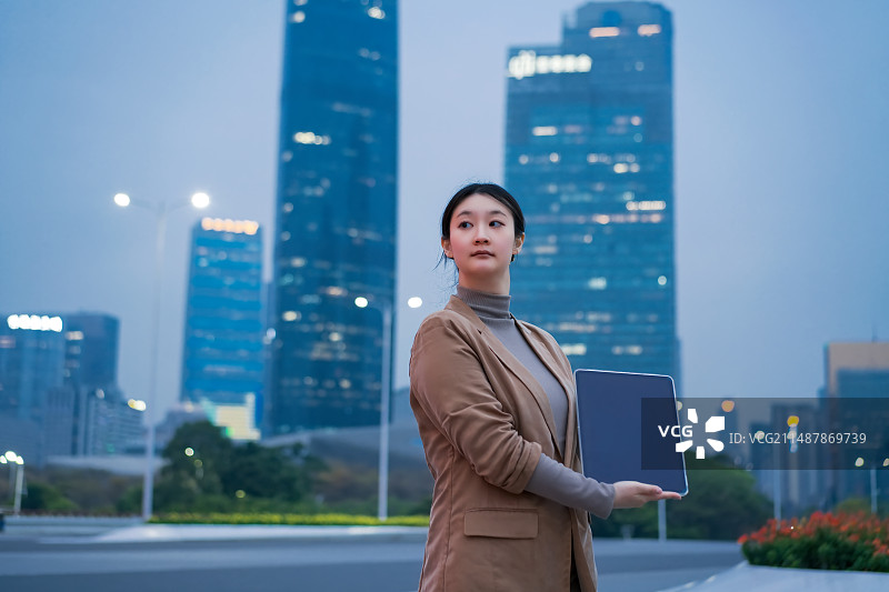 自信的女商人与笔记本电脑在城市环境图片素材