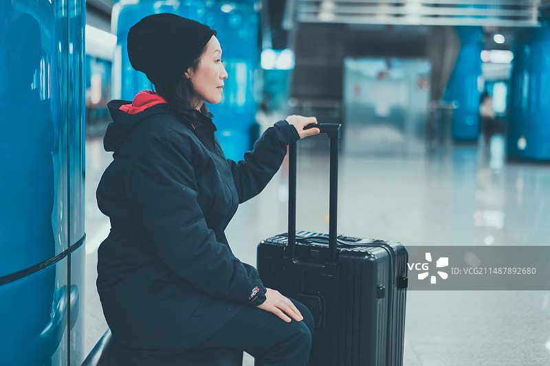 一名妇女拿着行李在地铁站耐心等候图片素材