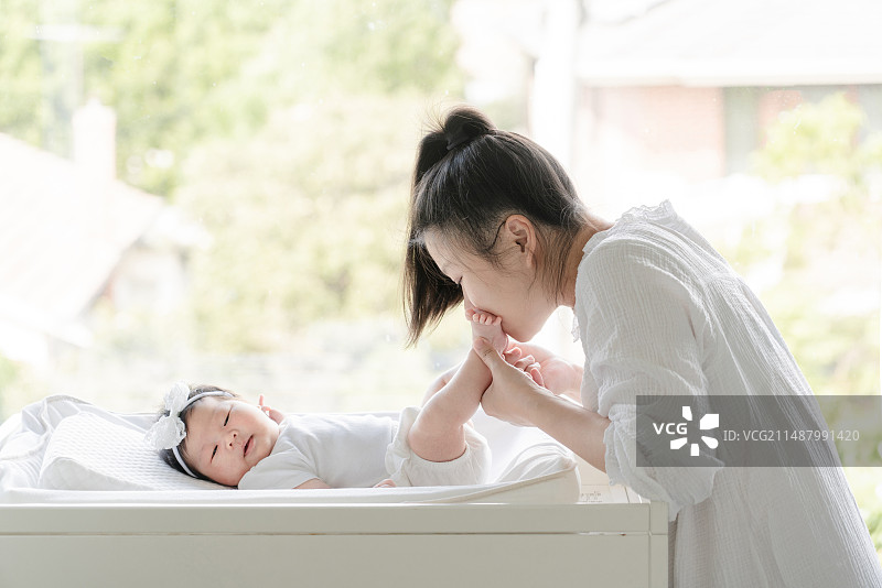 妈妈亲吻满月的新生女婴的脚图片素材