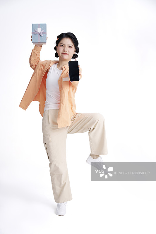手拿礼物与手机的年轻中国女人图片素材