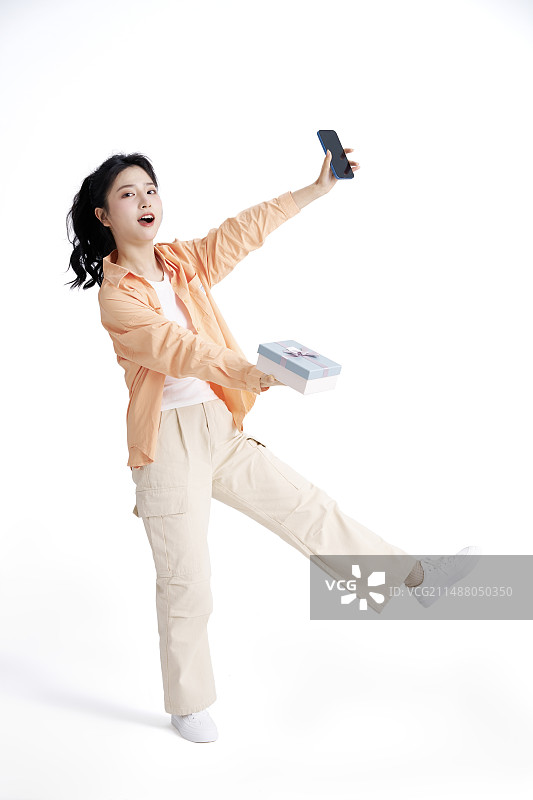 手拿礼物与手机的年轻中国女人图片素材