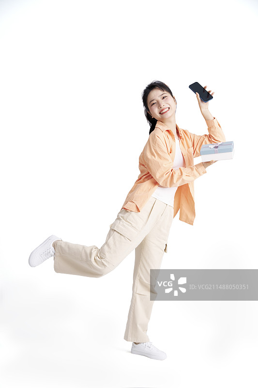 手拿礼物与手机的年轻中国女人图片素材