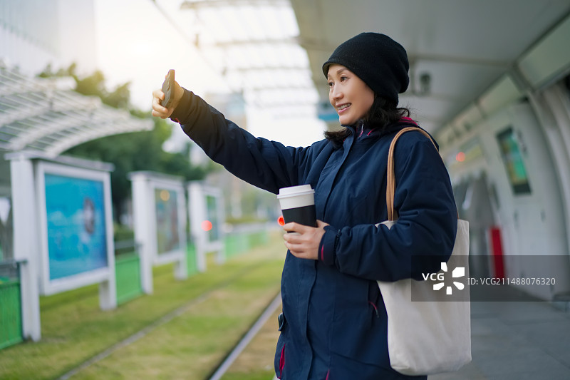 年轻女子在城市环境中用咖啡叫出租车图片素材