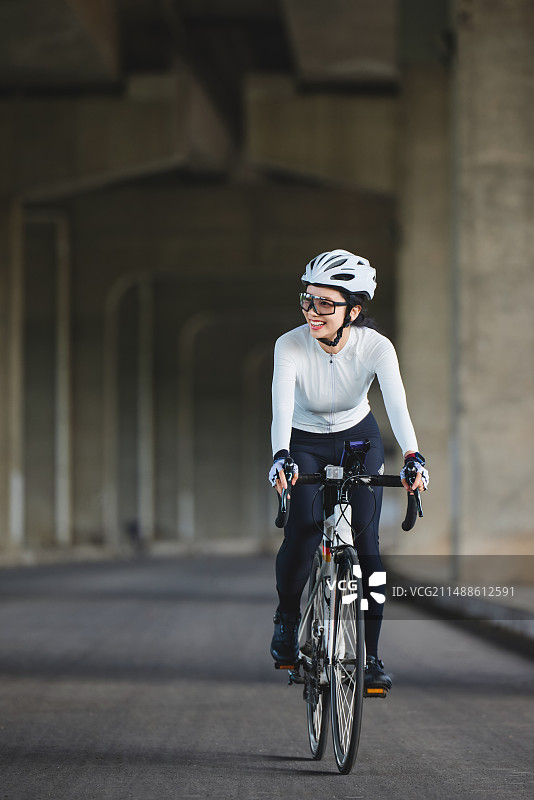 城市高架桥下骑行的年轻美女图片素材