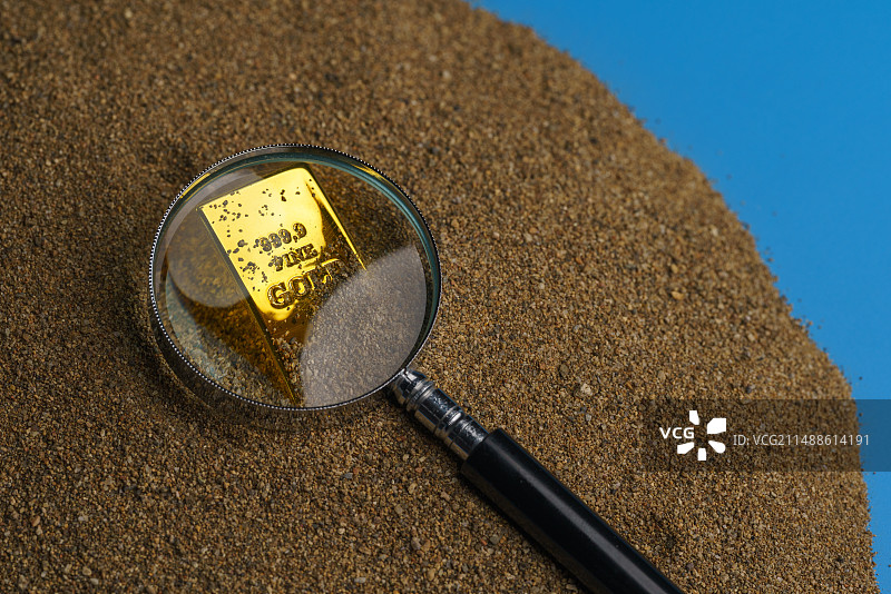 沙滩上用放大镜拍摄的高角度视角下黄金微缩创意图片素材