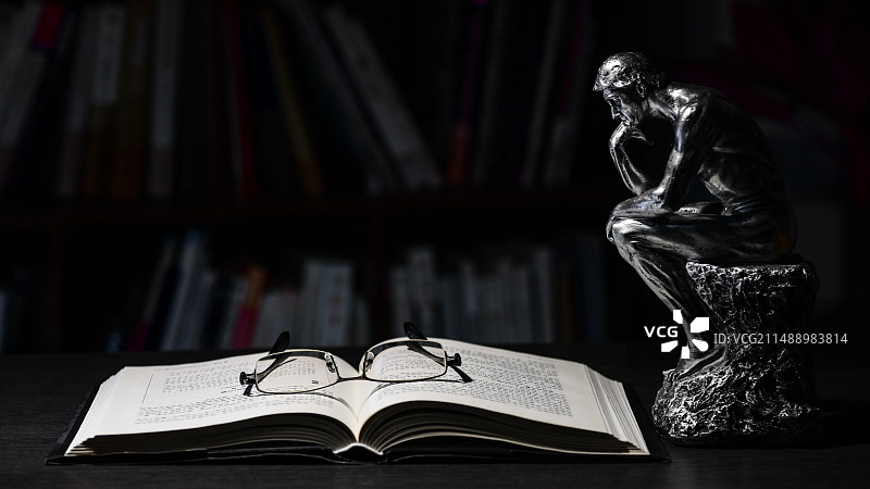 读书重在思考：桌上打开的书本和思想者雕塑特写图片素材
