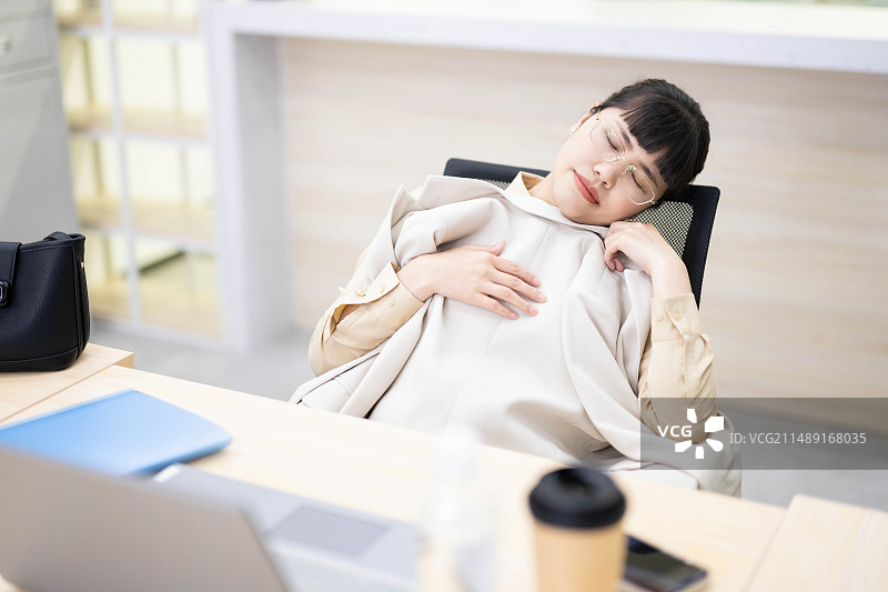 躺在办公椅上睡午觉的白领图片素材