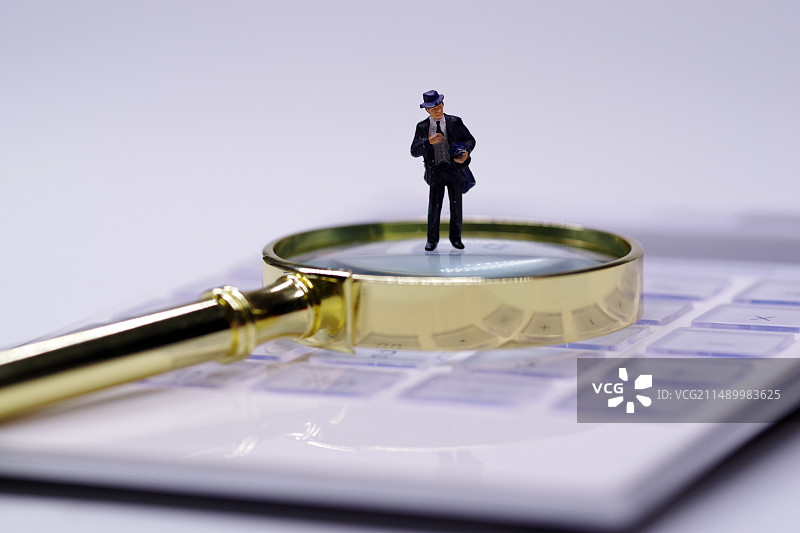 商务人士使用计算器放大镜图片素材
