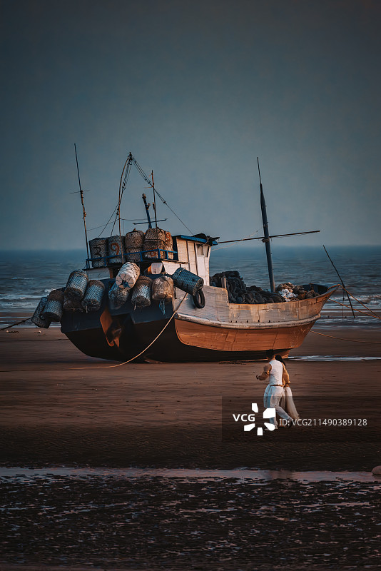 海滩上搁浅的船和拍婚纱照的人图片素材