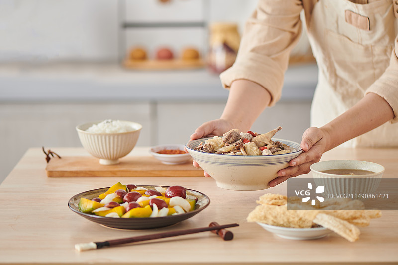 年轻女人往餐桌上端菜图片素材