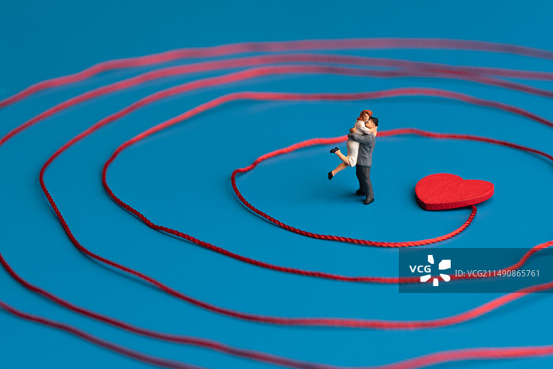 站在红线环绕内红心处拥抱的恋人微缩创意图片素材