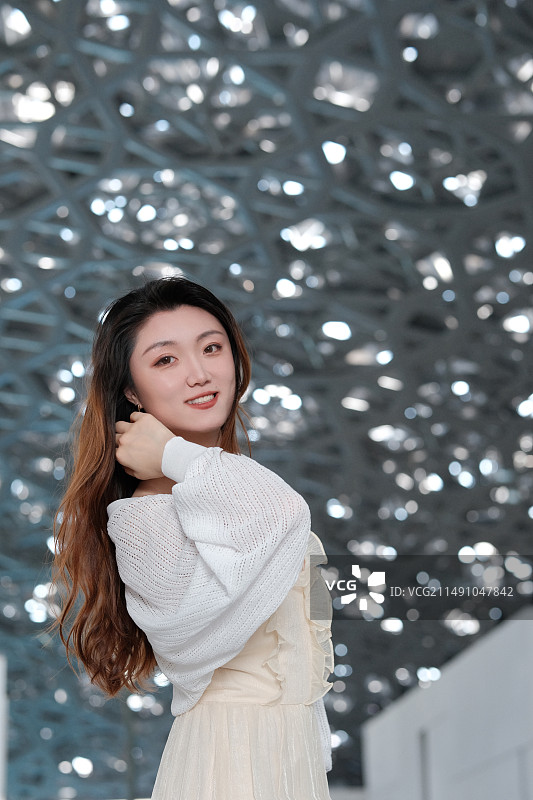 站在美术馆星空顶下的微笑年轻女子画像图片素材