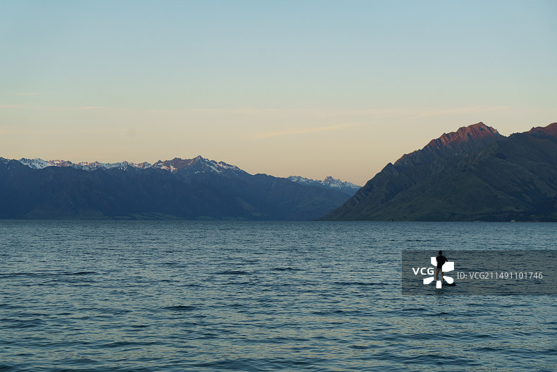 日落时在瓦纳卡湖划桨板的人图片素材