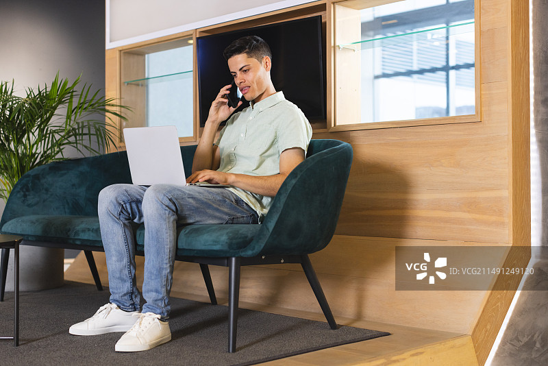 在现代商务办公室内用笔记本电脑通话的混血男人图片素材