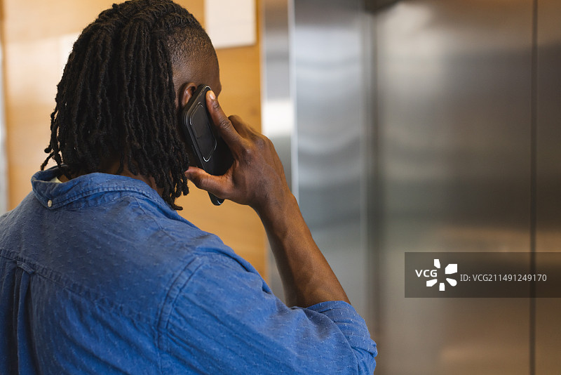 在现代商务办公室里用智能手机交谈的年轻非裔美国男子图片素材