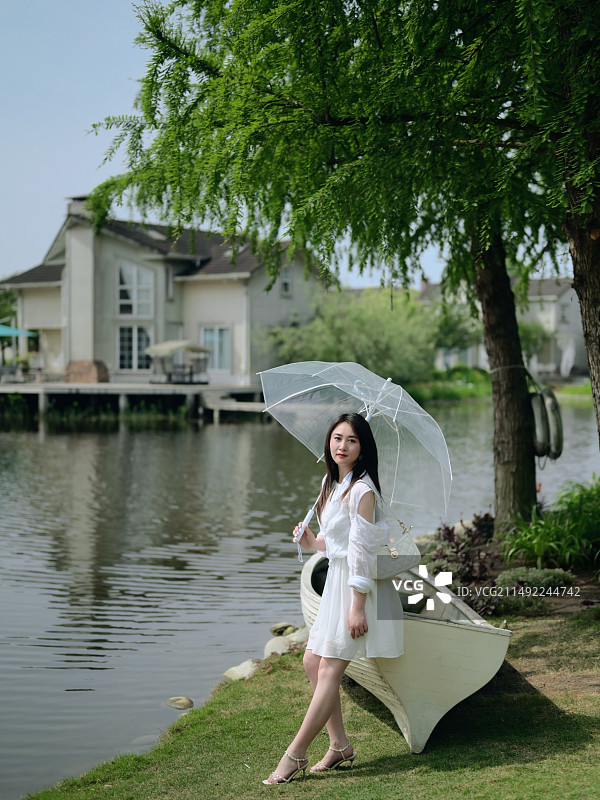 撑着伞的女人站在湖边图片素材