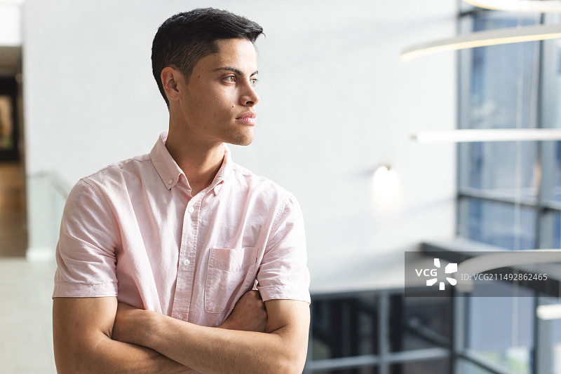 在现代化的办公室里，一位年轻的混血男人深色头发，若有所思地凝视着图片素材