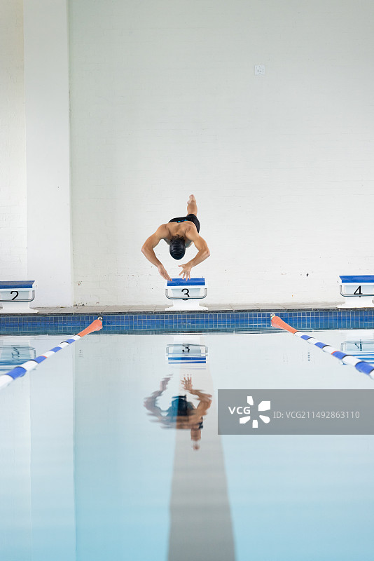 年轻的白人游泳运动员从起跳台跳入泳池，留白图片素材