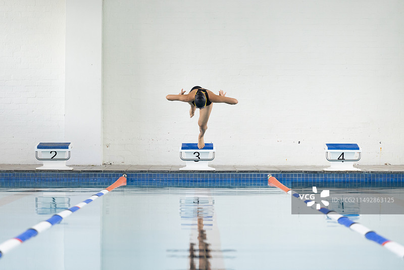 混血女孩跳入泳池，身穿黑色泳衣，留白图片素材