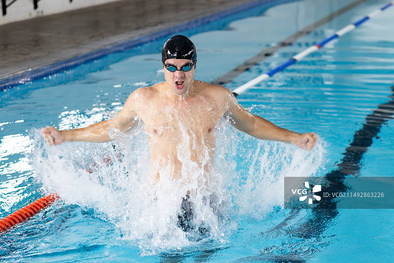 在室内游泳池训练，激起水花的年轻白人游泳运动员图片素材