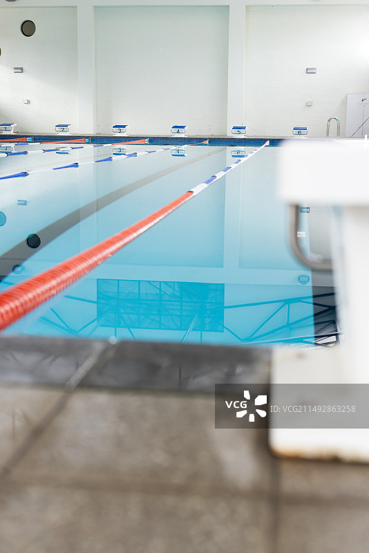 戴着泳帽和泳镜的游泳者在室内游泳池比赛，留白图片素材