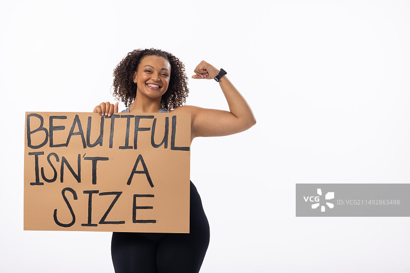 混血加大码年轻女性展示手臂肌肉，手持海报，白色背景，留白图片素材