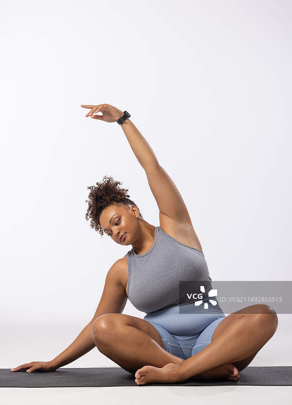 混血年轻女性加大码模特在白色背景上伸展身体，留白区域图片素材